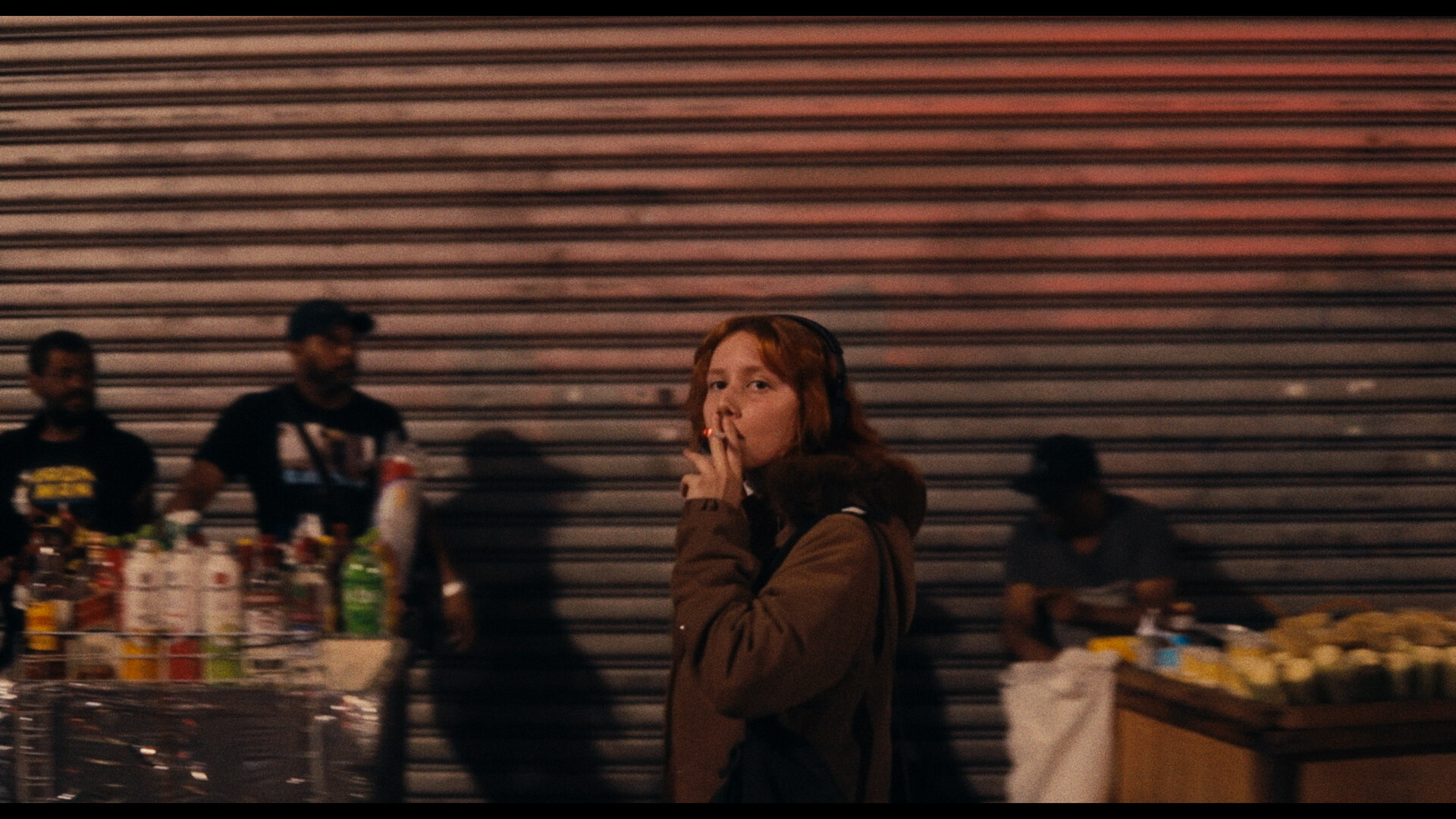 Jovem ruiva diante de uma barraca de rua à noite