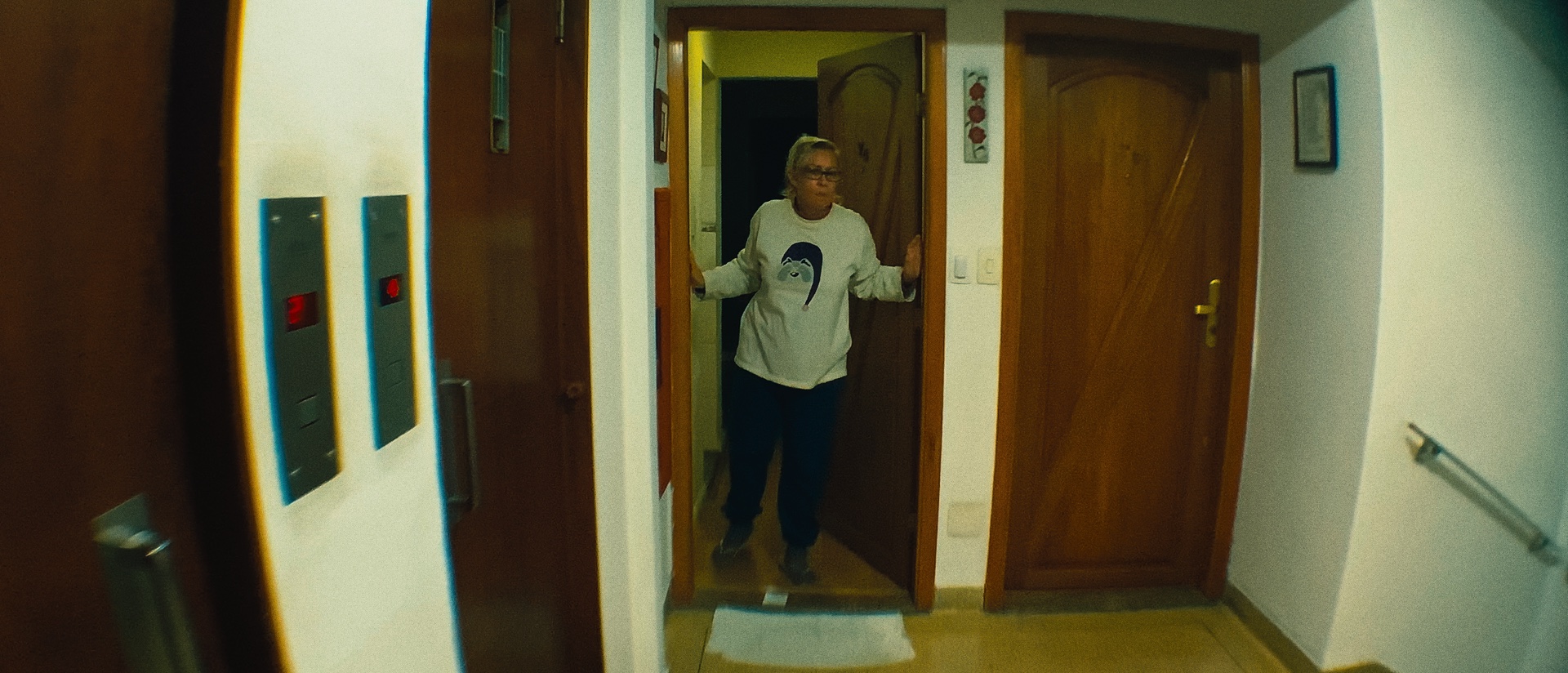 Personagem surge entre duas portas em um corredor iluminado