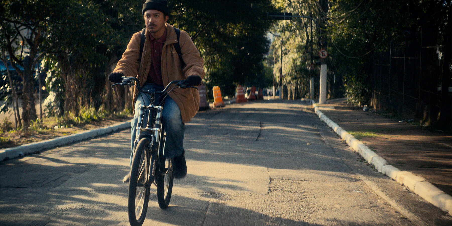 Personagem de bicicleta em uma rua arborizada