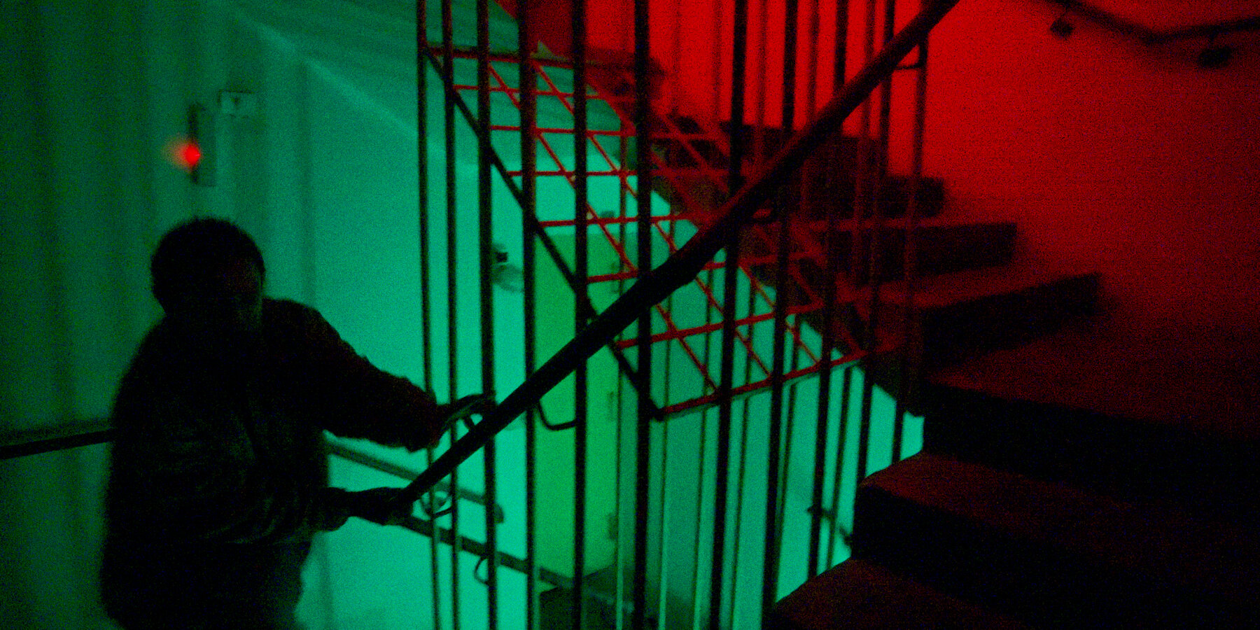 Pessoa em uma escadaria sob luz verde e vermelha